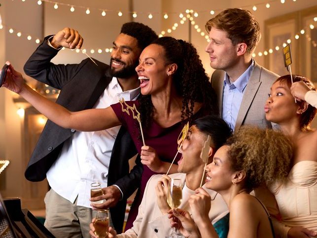People at a party waving to a laptop screen